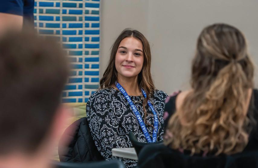 A student smiling while listening to someone speak